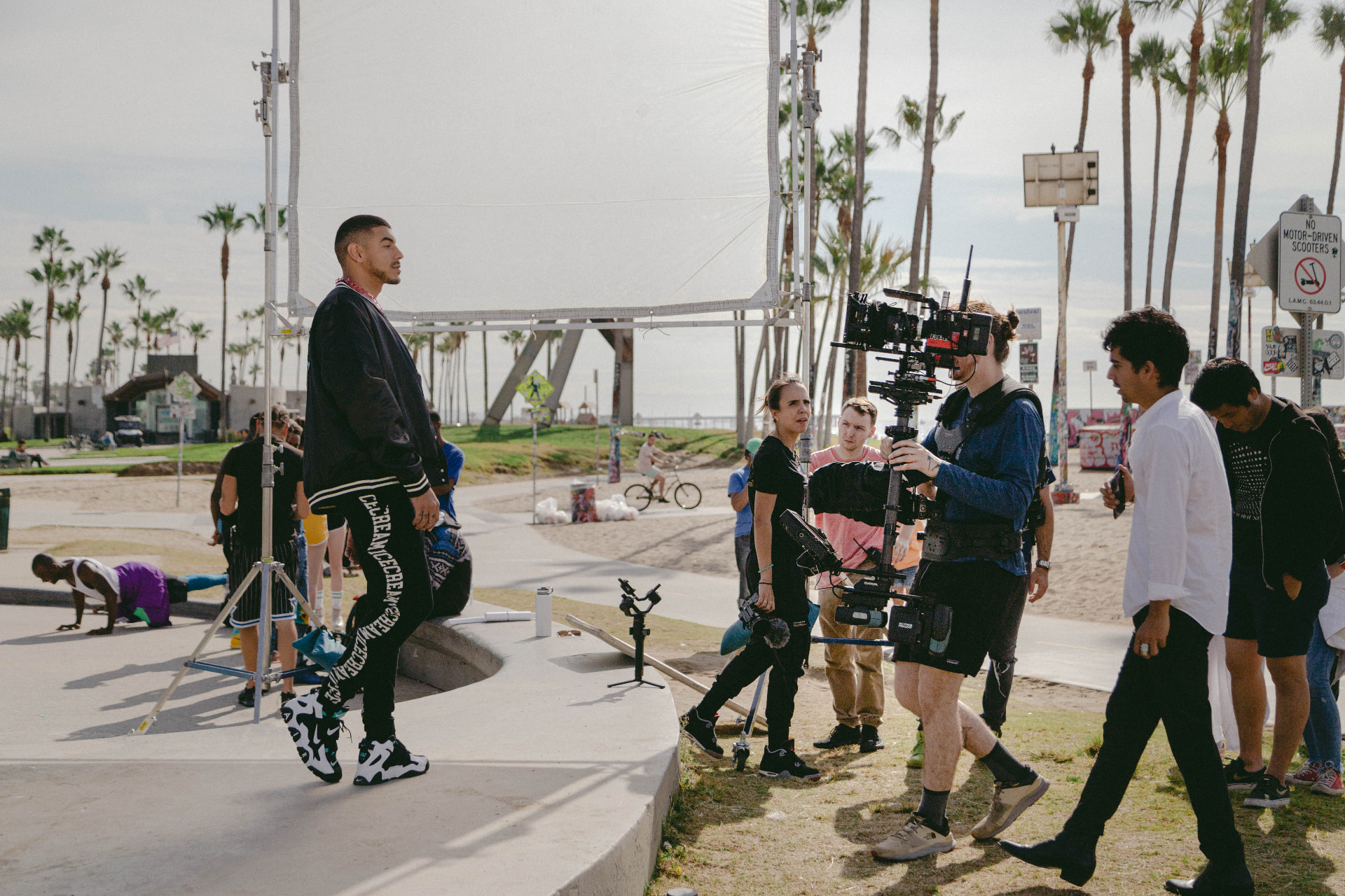 Film crew and performer working beside a diffusion screen near the beach